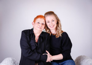 alt="daughter in law holding hands while sitting down with hers red headed mother in law"