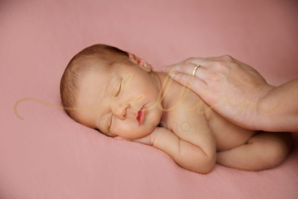 alt="newborn baby girl on a pink blanket"