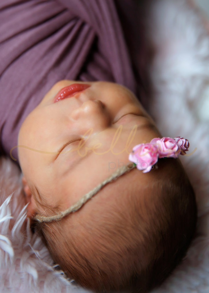 alt="newborn baby girl with a pink flower headband"