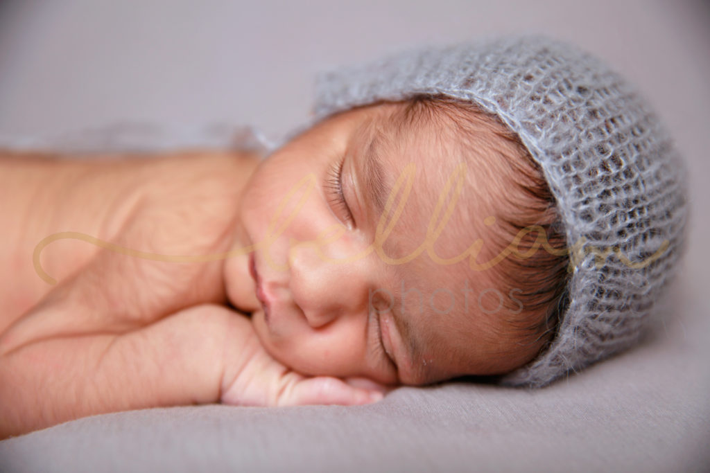 alt="newborn baby boy on a grey blanket with a grey mohair hat on"