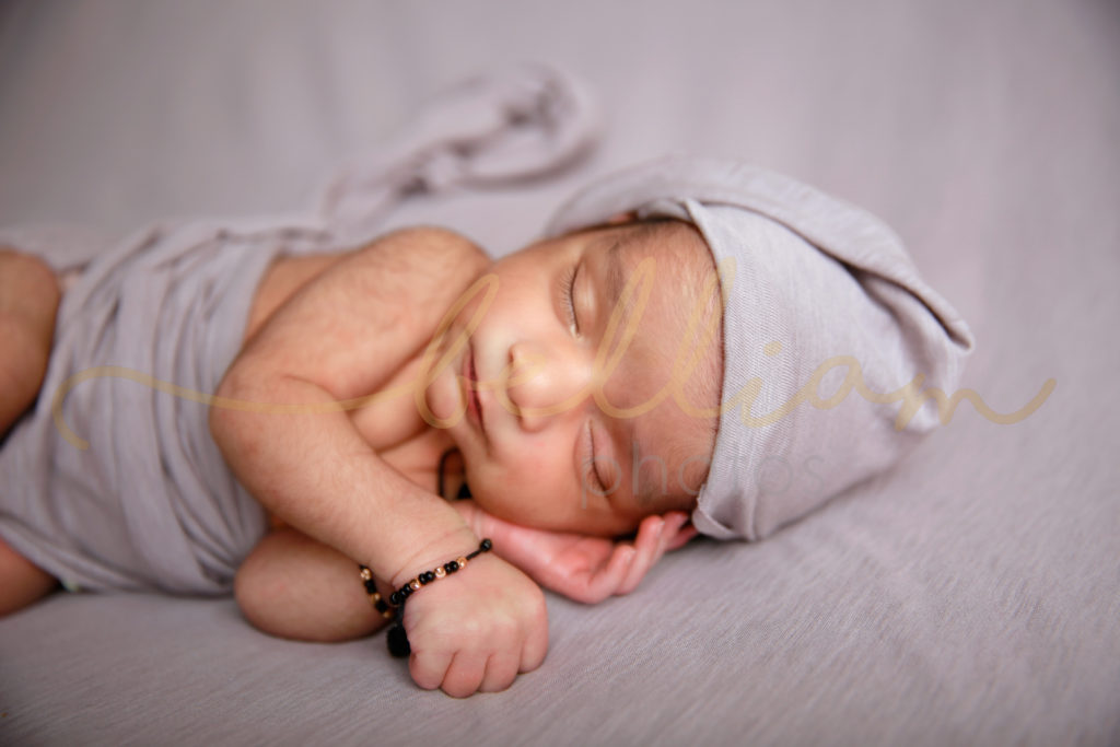 alt="newborn baby boy wrapped up posed with a hat"