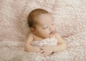 alt="newborn baby girl on a pink furry blanket"