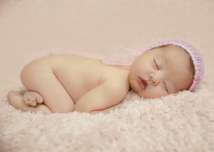alt="calgary newborn pictures baby girl on a pink furry blanket with pink mohair hat"