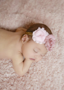 alt="calgary newborn pictures baby girl on a pink furry blanket with pink and gold headband"