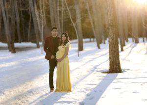 alt="beautiful mother to be in a yellow maternity gown standing with her husband at sunset"