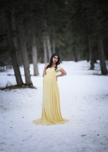 alt="beautiful mother to be in a yellow maternity gown in a park at sunset"