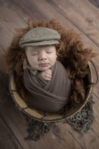 newborn baby boy in a brown wrap in a basket
