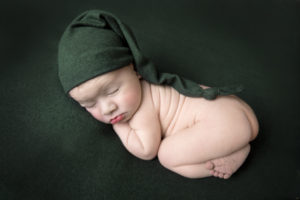 newborn baby boy green hat on a green backdrop