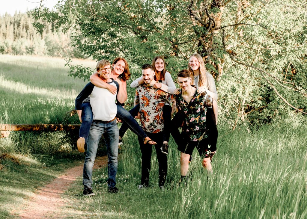 family of five in a field cuddled for a photo for Belliam Photos by Wendy Goetz Calgary Family Photographer