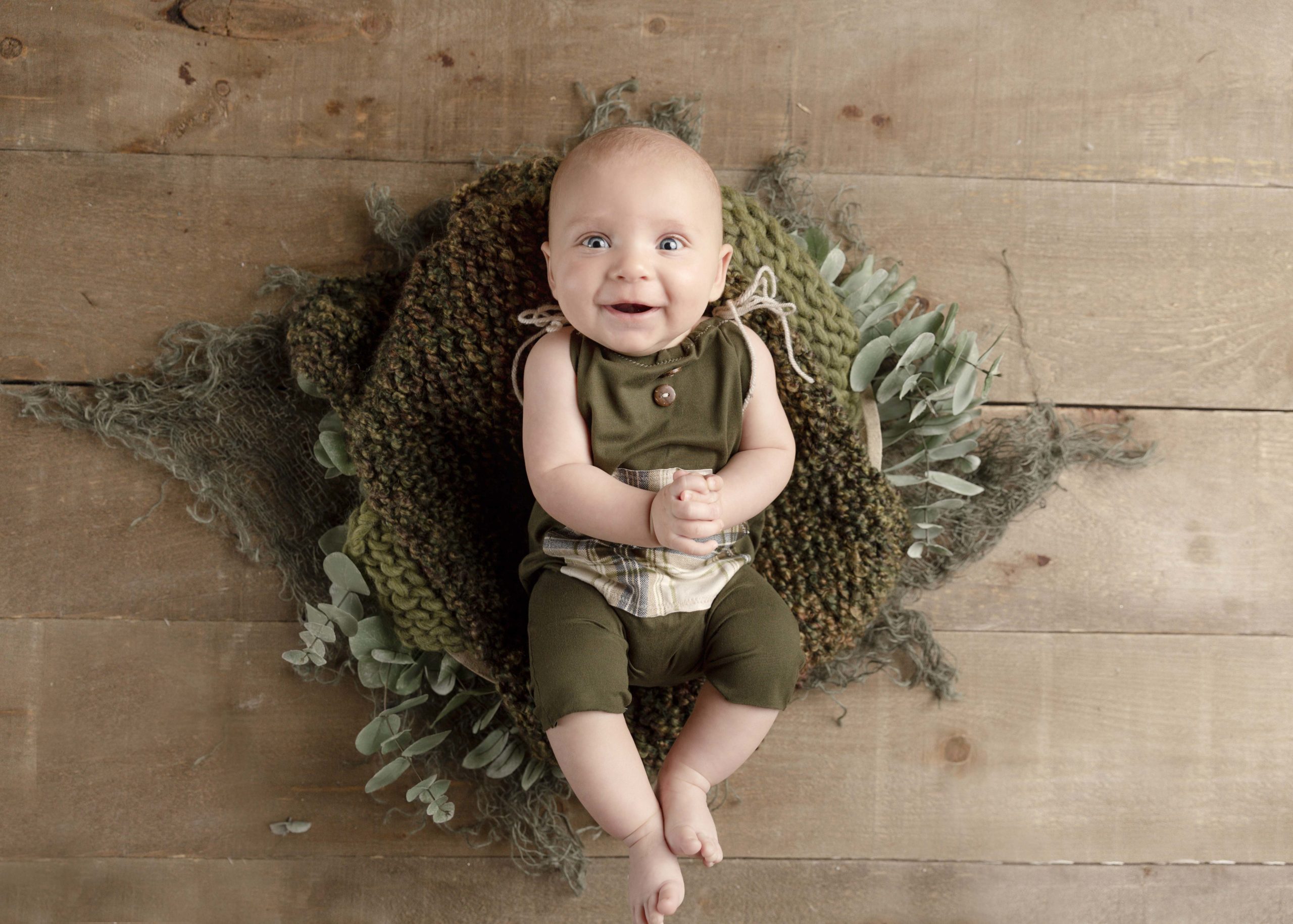 3 month old baby in a green onsie on a green blanket wrapped in a bl Calgary baby photographer Belliam Photos