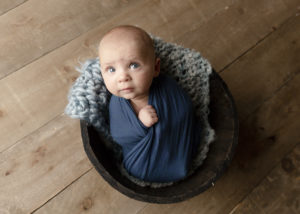 3 month old baby wrapped in a blue wrap in a bucket Calgary baby photographer Belliam Photos