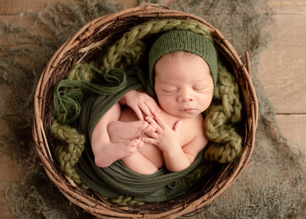 newborn boy in a bowl in green