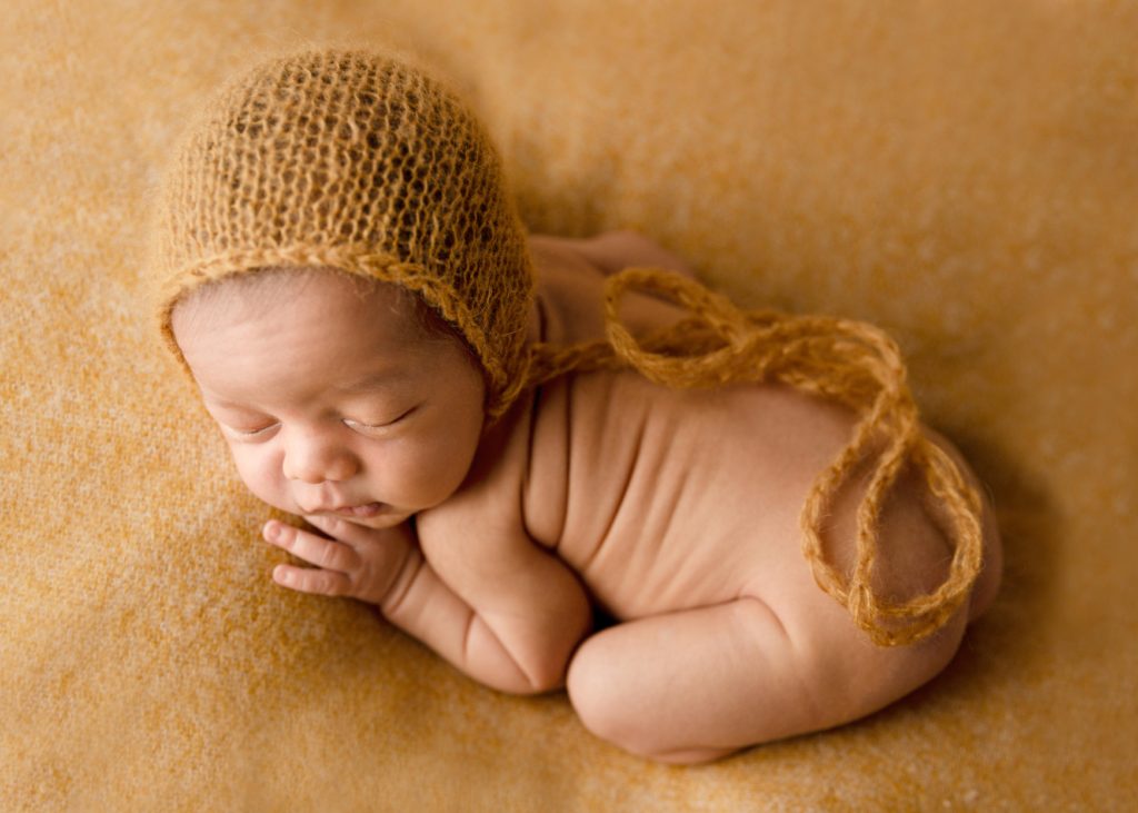 newborn baby boy on mustard blanket
