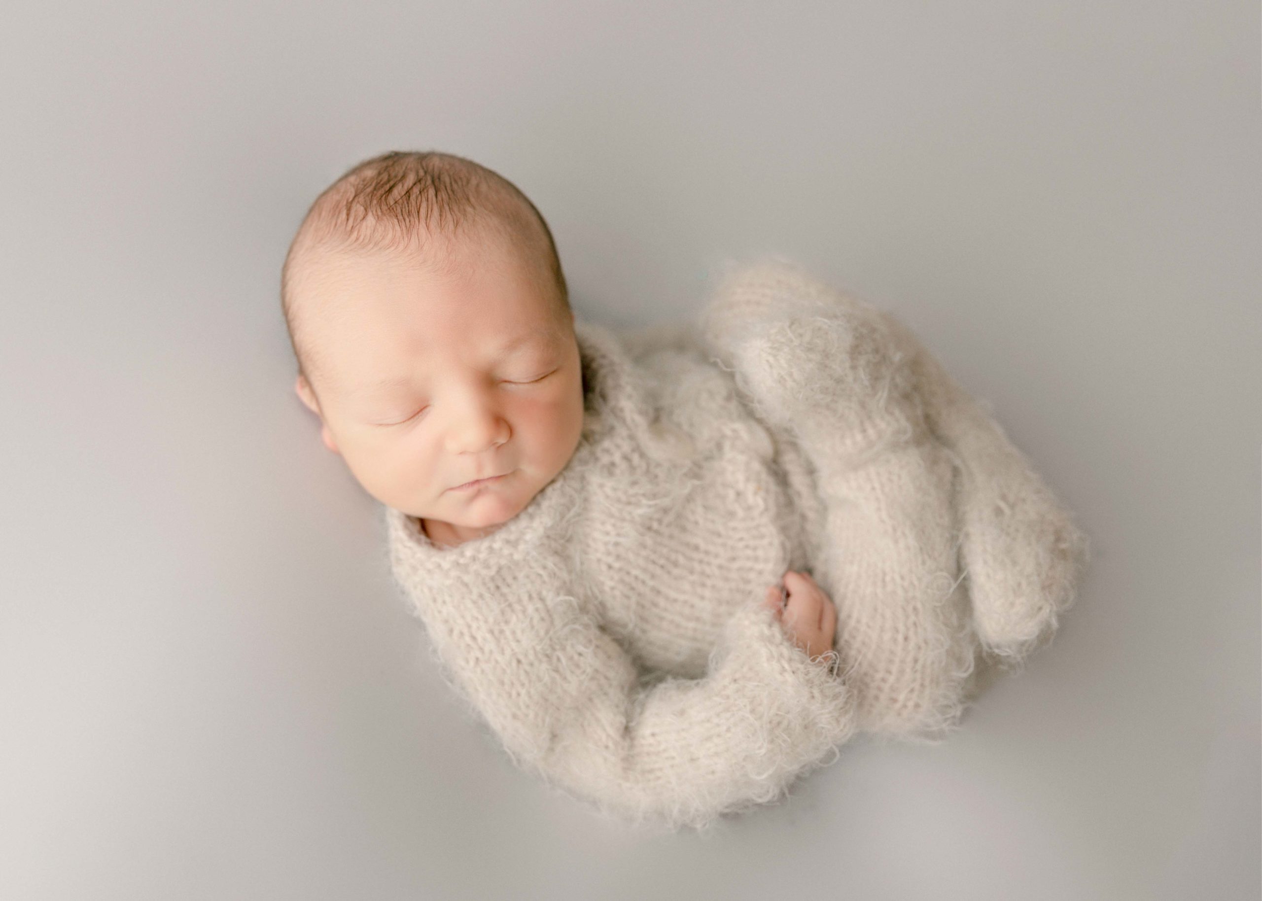 Newborn Boy on a white backdrop on his back