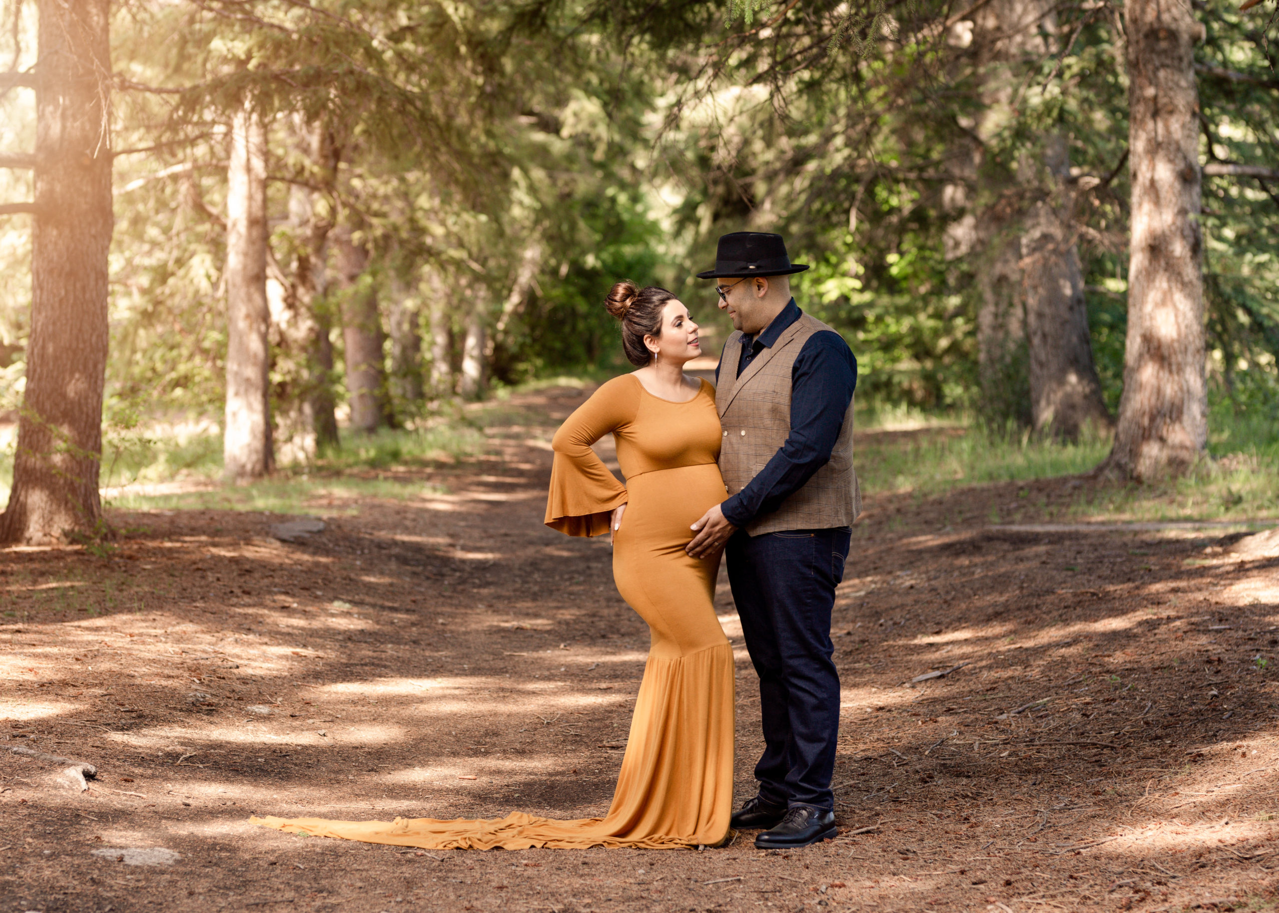 Couple standing close together woman in mustard colored dress maternity photo