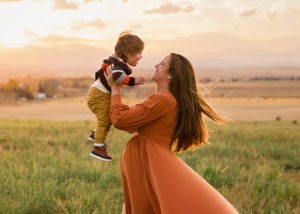Pregnant mom in a field holding her toddler up Fall Photoshoot