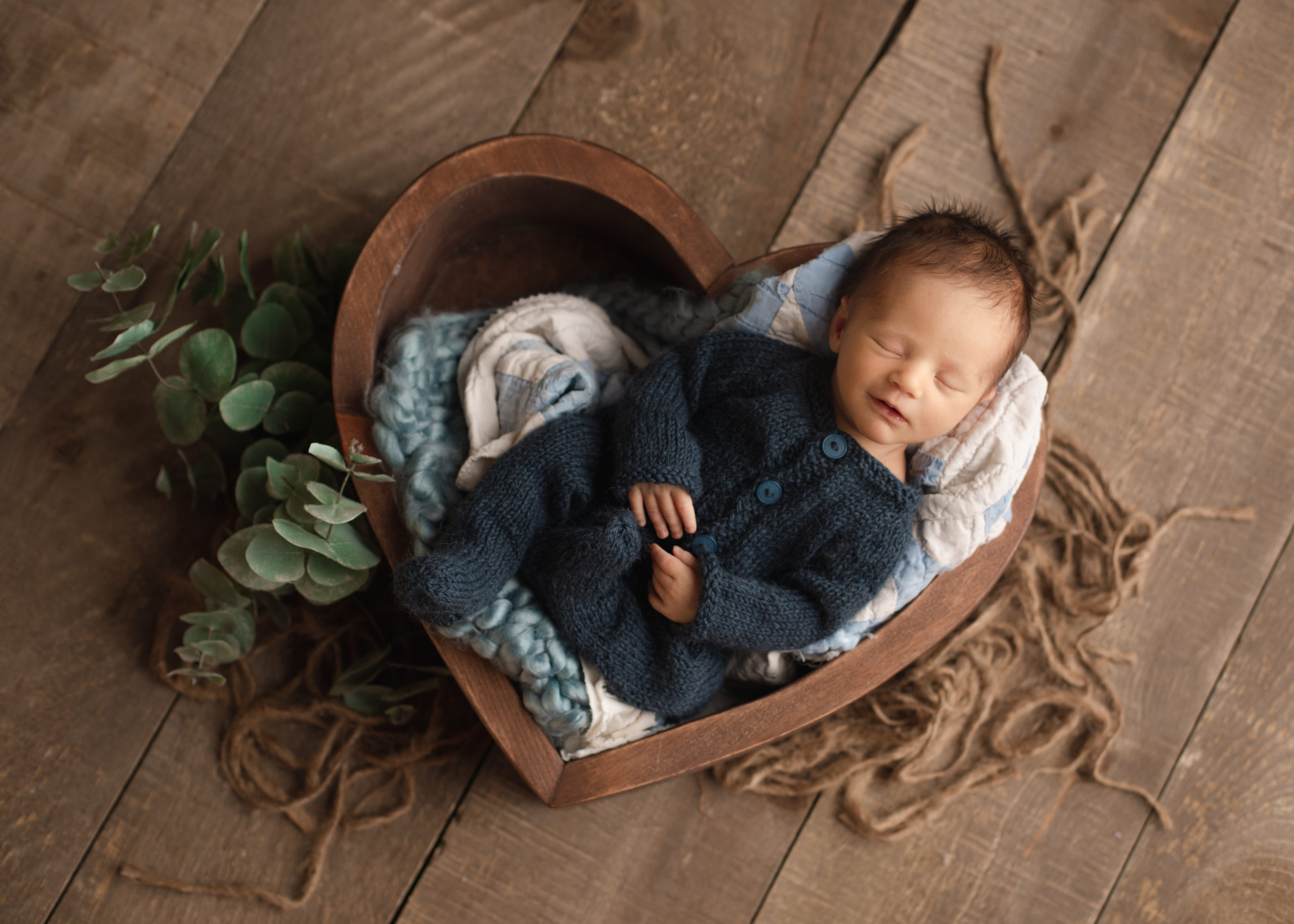 baby boy in a heart shaped bowl in a blue romper