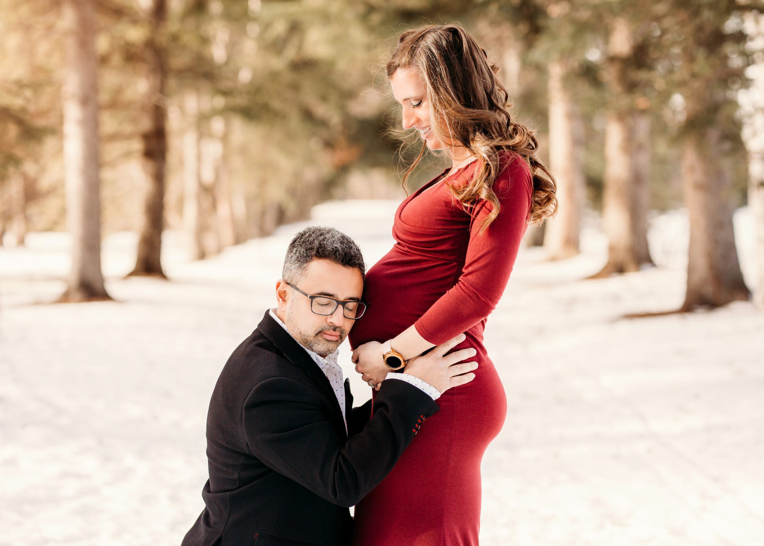 Pregnant lady standing with husband with his head to her belly