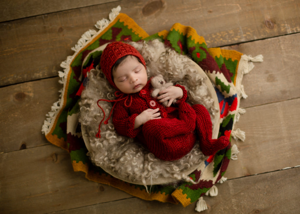 Newborn baby in a red knit outfit in a basket | Infant Swim Lessons Calgary